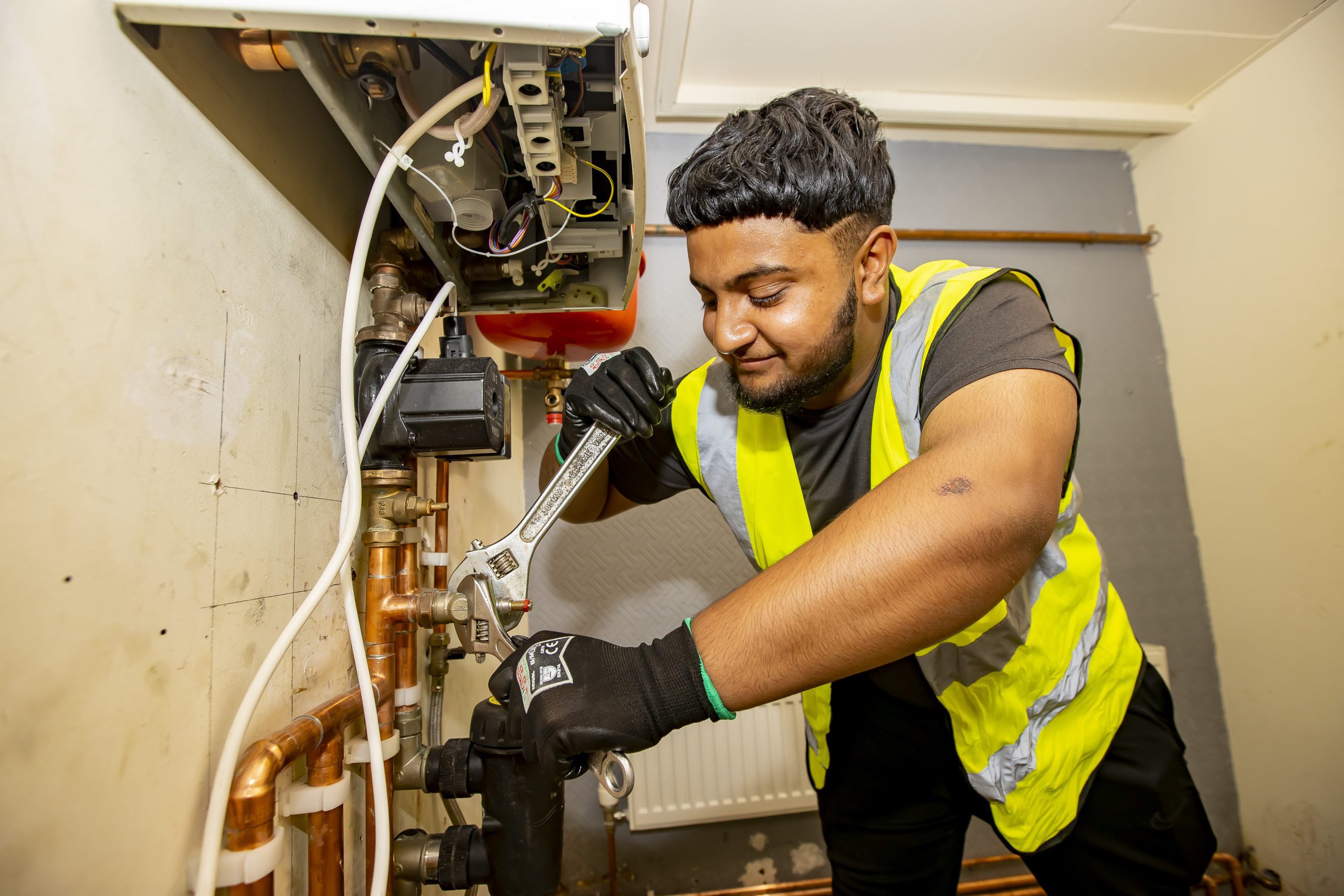 Plumbing student holding fixing a pipe joint with a spanner