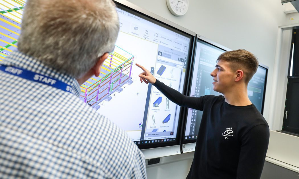 Student with teacher looking at a large screen showing a technical construction drawing
