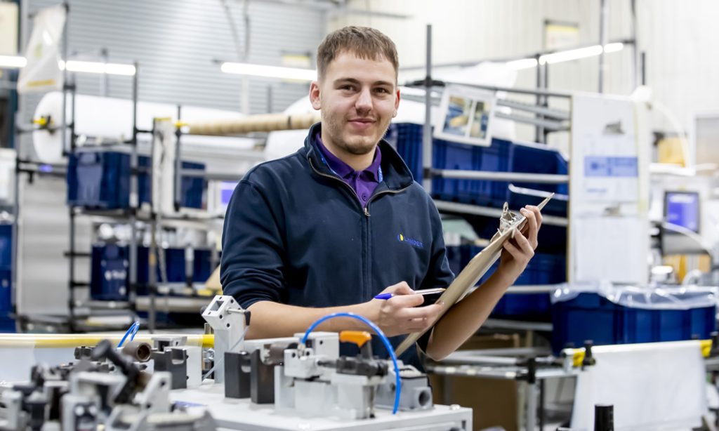 Male Engineering Student in the workshop holding a clipboard