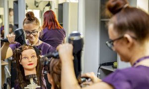 Hairdressing student practicing a blow dry on a dummy head