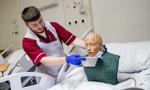 Health care student helping a dummy patient as they feel sixk